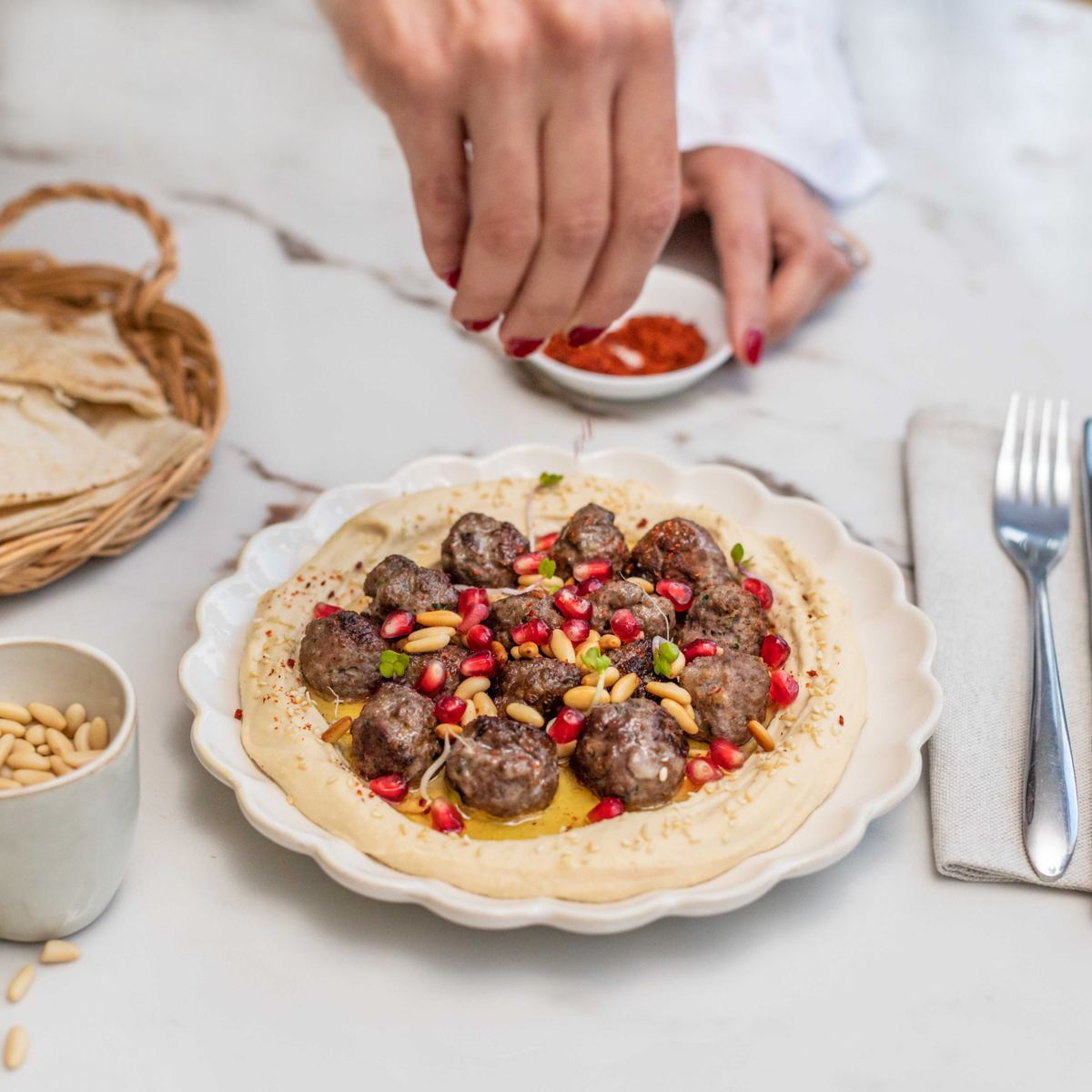 Houmous garni de boulettes, de grenade et de pignons